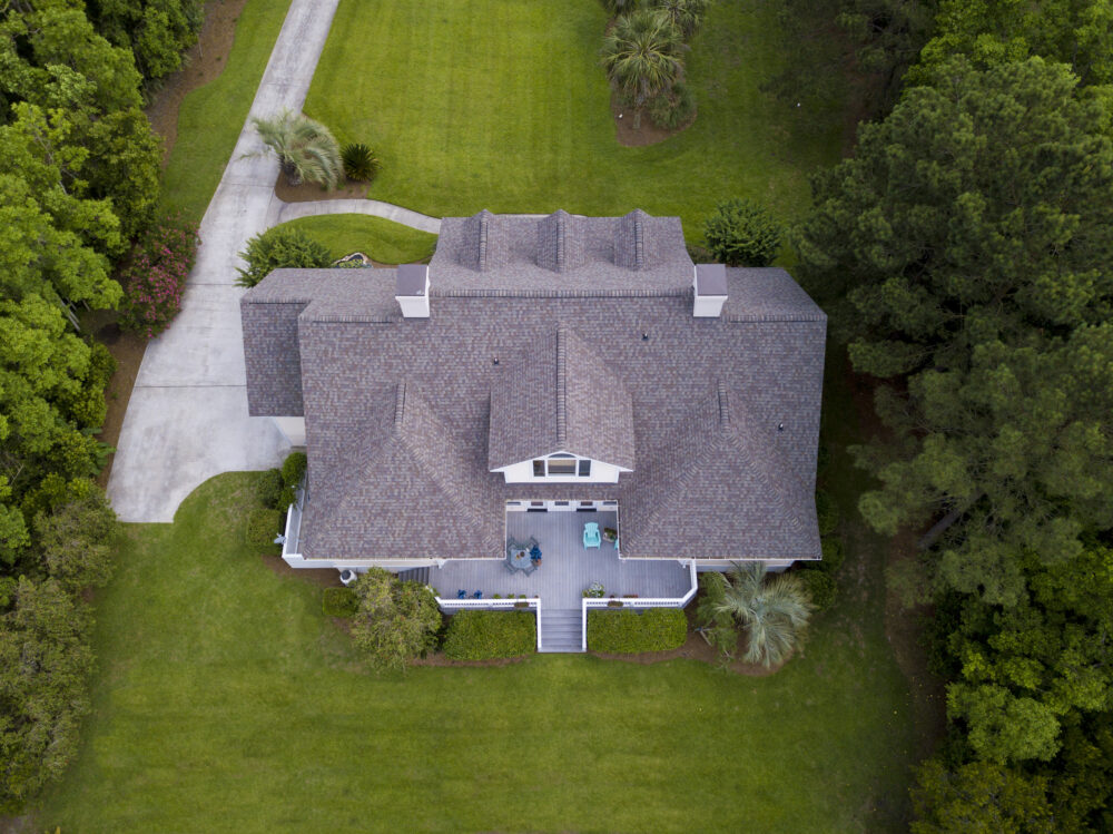 Aerial view of a large two-story home with a shingle roof and landscaped yard